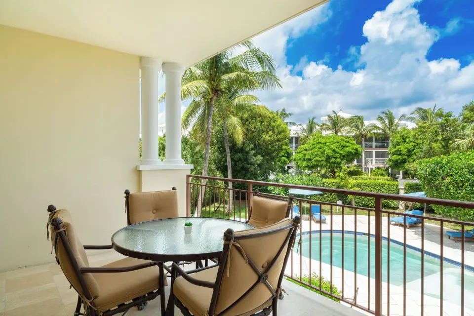 Deluxe Studio balcony with dining table overlooking pool and palms at Villa del Mar.