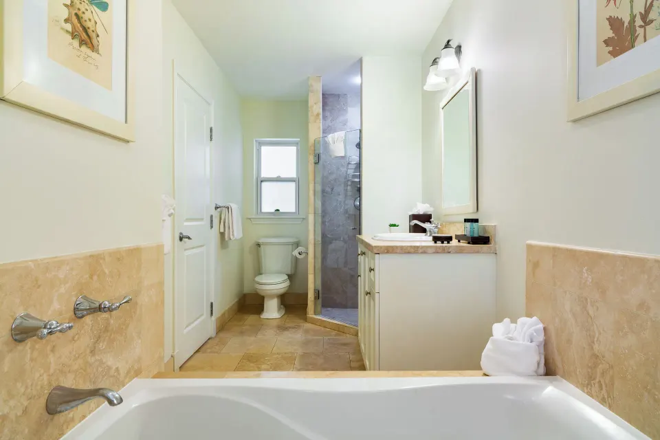 Deluxe Studio bathroom with tub, vanity, toilet, and glass shower at Villa del Mar.