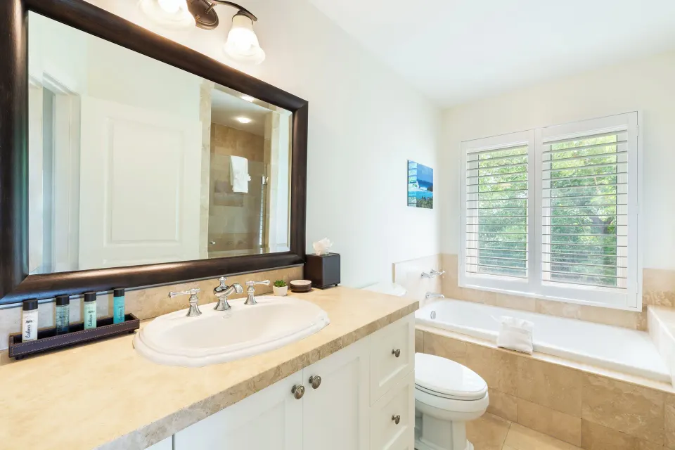 Luxury Suite bathroom with vanity, bathtub, shutters, and amenities at Villa del Mar.
