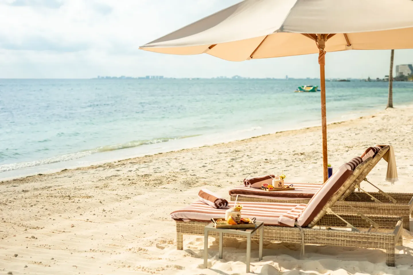 Beach loungers with umbrella and refreshments at Villa del Palmar Cancun Beach Resort & Spa.