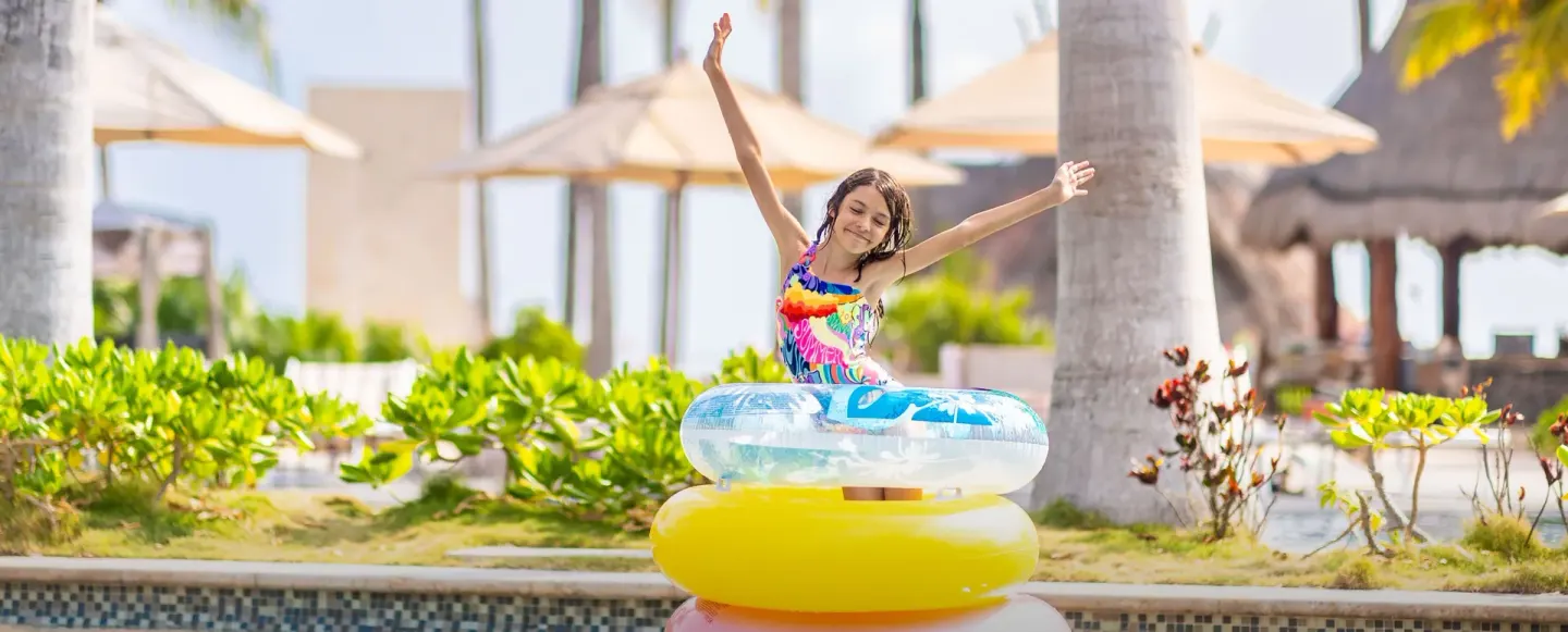Girl posing on stacked pool floats by the pool at Villa del Palmar Cancun Beach Resort & Spa.