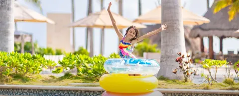 Girl posing on stacked pool floats by the pool at Villa del Palmar Cancun Beach Resort & Spa.