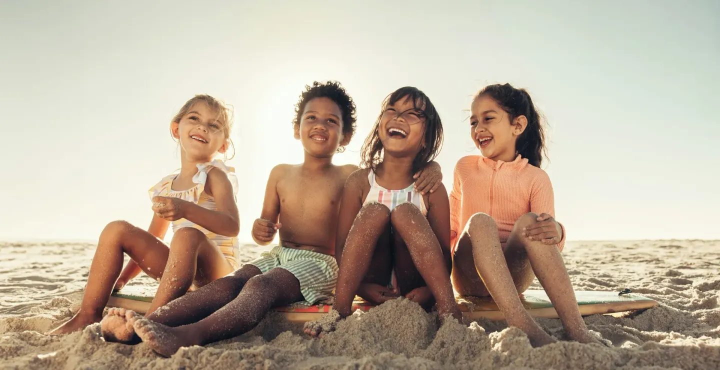 Children sitting together on the sandy beach at Villa del Palmar Cancun Beach Resort & Spa.