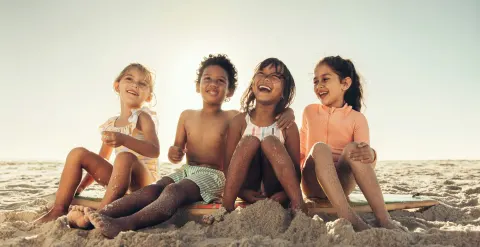 Children sitting together on the sandy beach at Villa del Palmar Cancun Beach Resort & Spa.