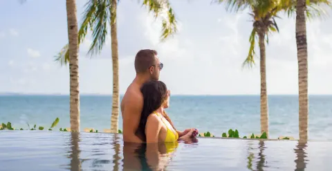 Couple in an infinity pool overlooking the sea at Villa del Palmar Cancun Beach Resort & Spa.