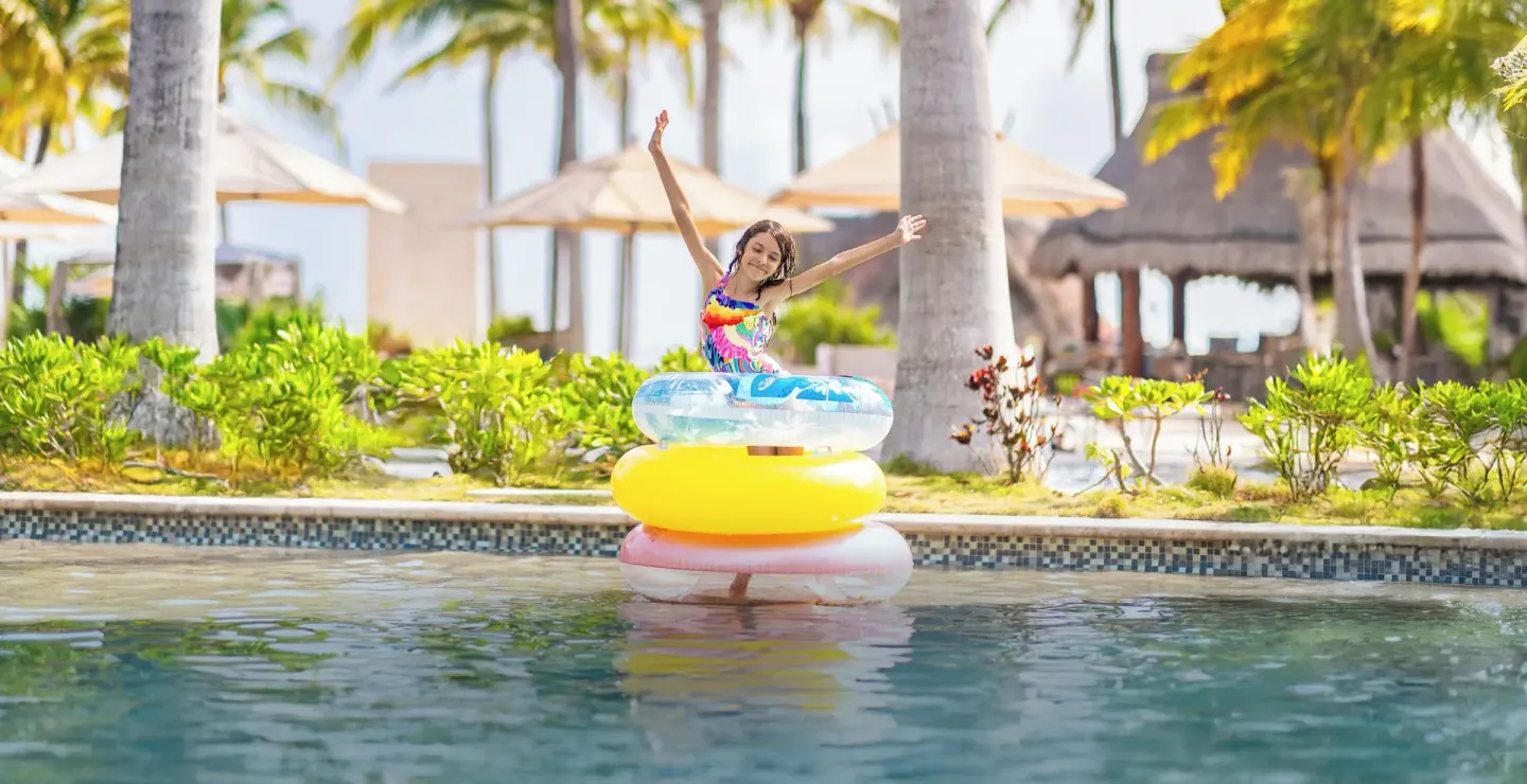 Child on colorful pool floats in the water at Villa del Palmar Cancun Beach Resort & Spa.