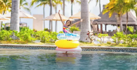 Child on colorful pool floats in the water at Villa del Palmar Cancun Beach Resort & Spa.