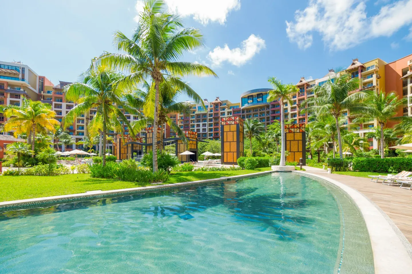 Resort pool, palms, and colorful buildings at Villa del Palmar Cancun Beach Resort & Spa.