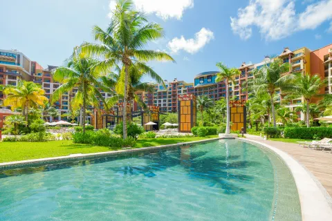 Resort pool, palms, and colorful buildings at Villa del Palmar Cancun Beach Resort & Spa.