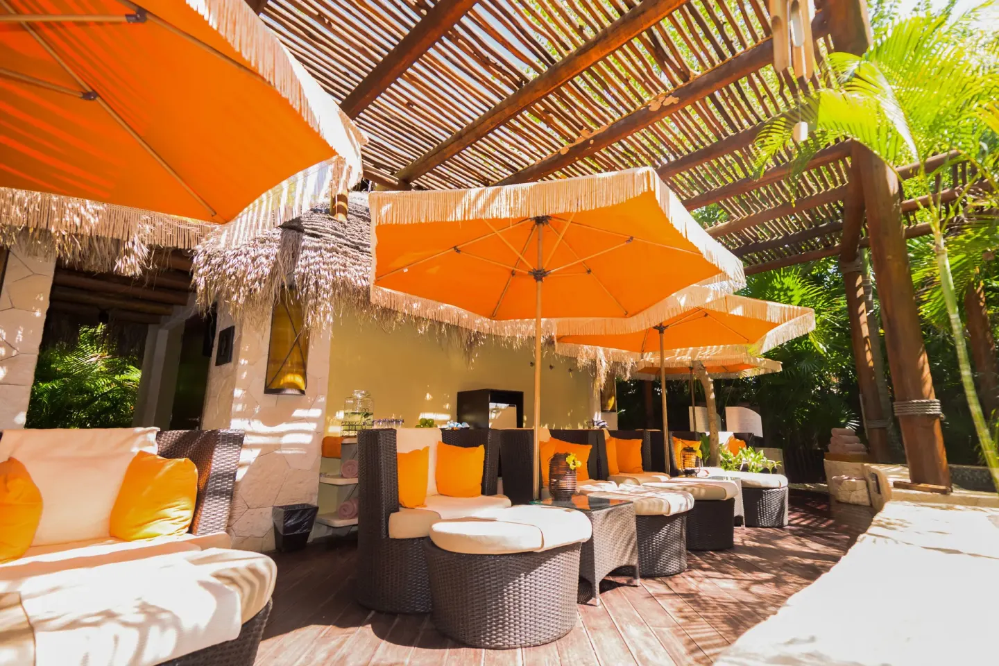 Shaded spa lounge chairs with orange umbrellas at Villa del Palmar Cancun Beach Resort & Spa.