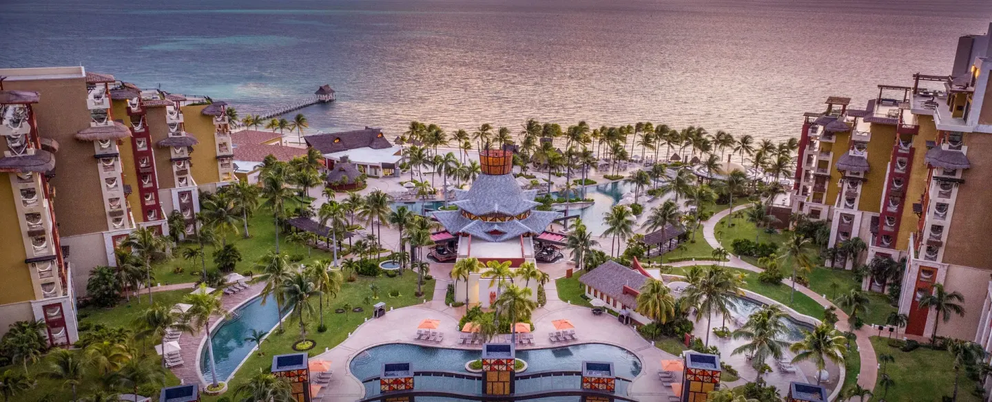 Twilight view of pools, palms, and beachfront at Villa del Palmar Cancun Beach Resort & Spa.