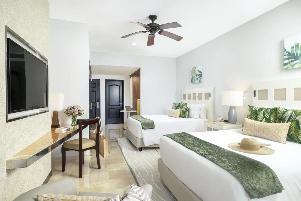 Deluxe room with two beds, desk, and wall-mounted TV at Villa del Palmar Cancun Beach Resort & Spa.