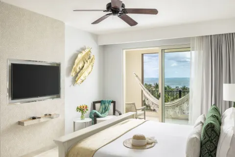 One Bedroom Ocean View king bedroom with TV and hammock at Villa del Palmar Cancun Beach Resort & Spa.