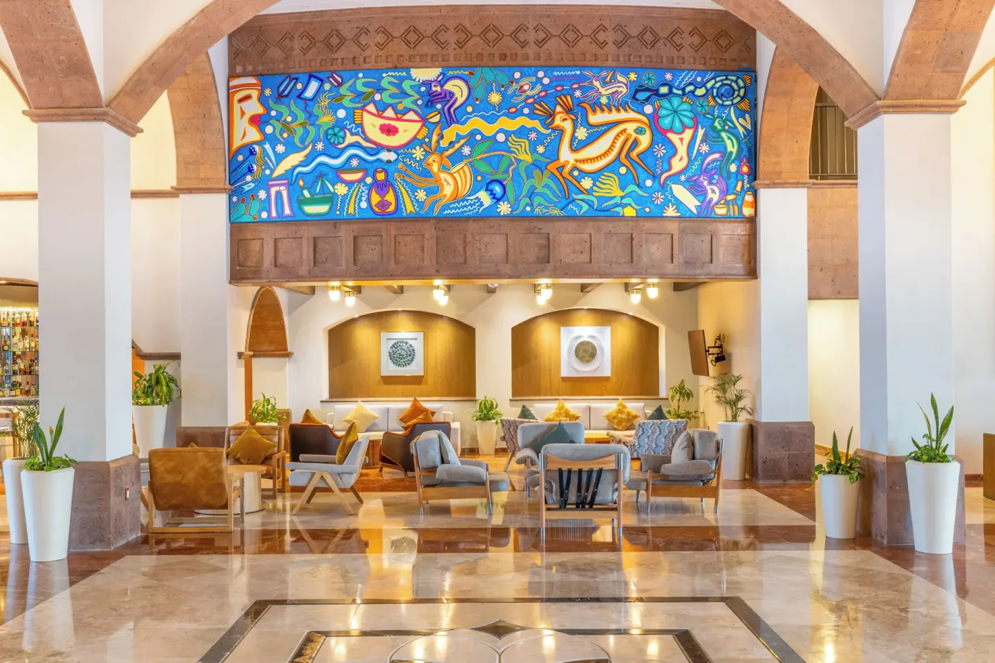 Lobby lounge seating under a bright mural at Villa Del Palmar Flamingos Beach Resort and Spa.