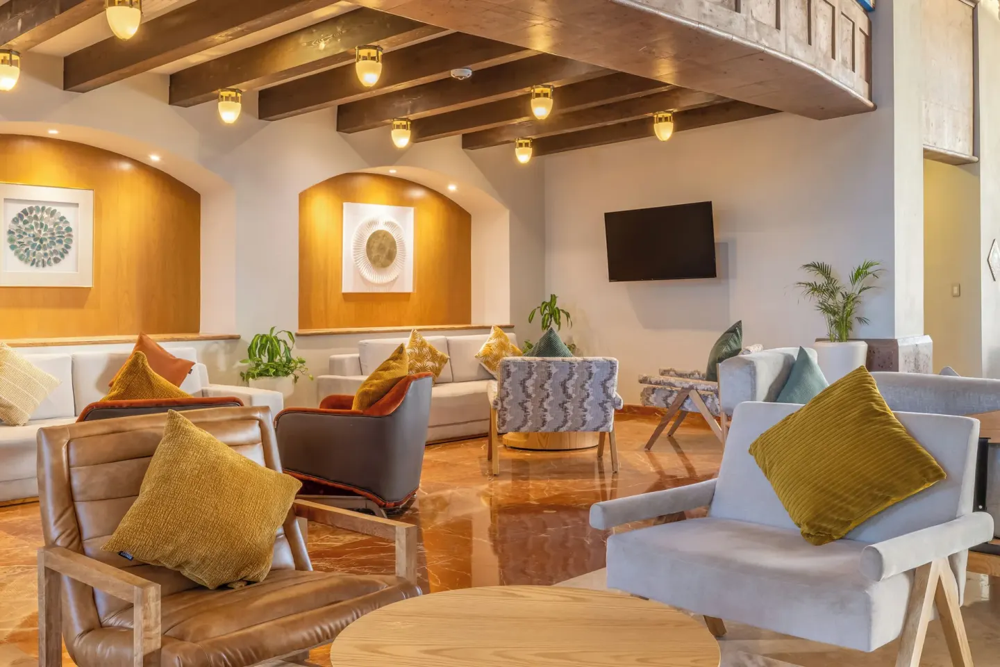 Lobby seating with armchairs, sofas, and wall art at Villa Del Palmar Flamingos Beach Resort and Spa.