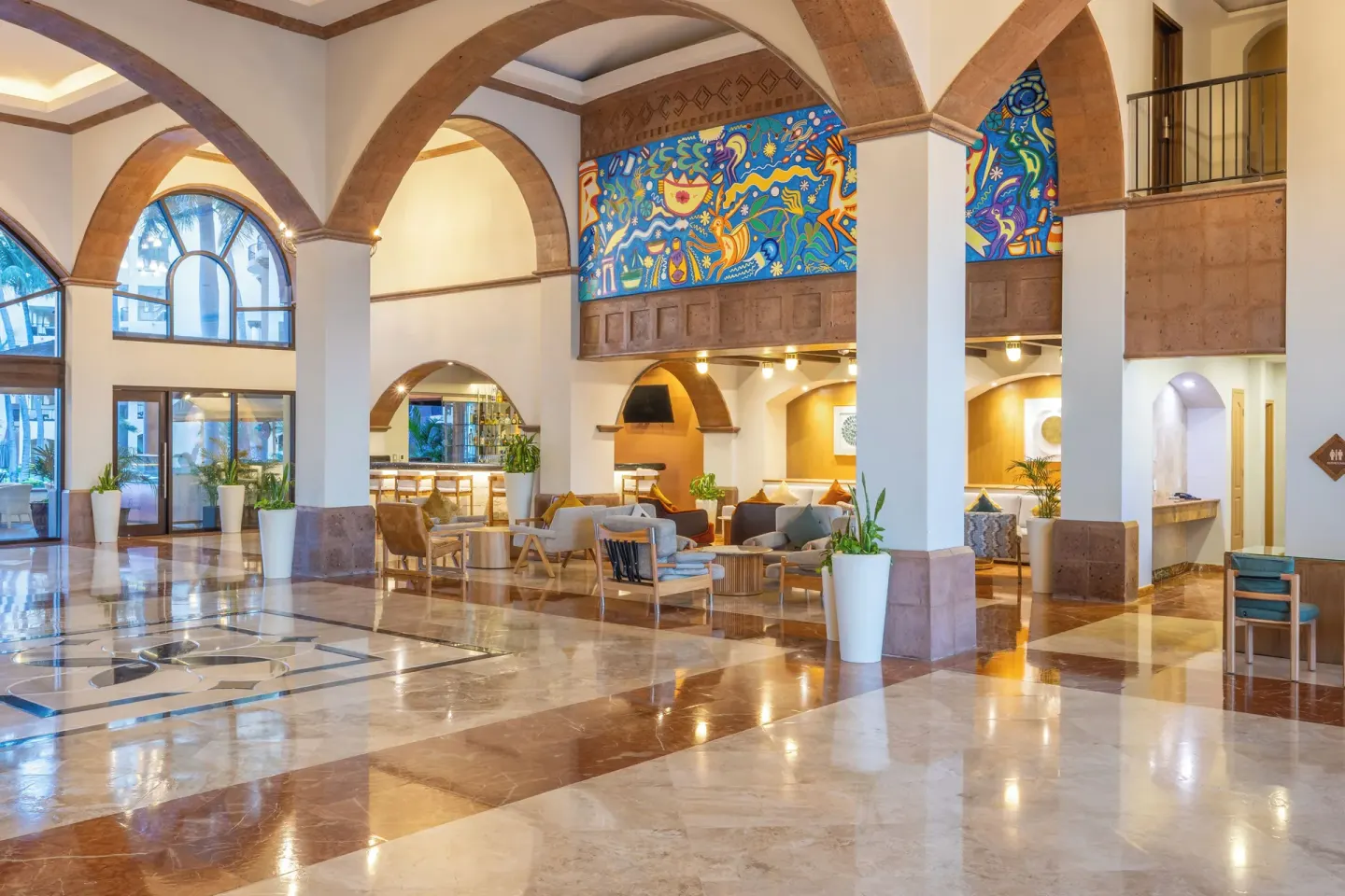 Lobby seating beneath colorful mural panels at Villa Del Palmar Flamingos Beach Resort and Spa.