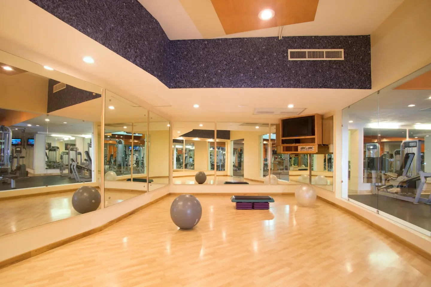 Mirrored exercise studio with wood floor at Villa Del Palmar Flamingos Beach Resort and Spa.