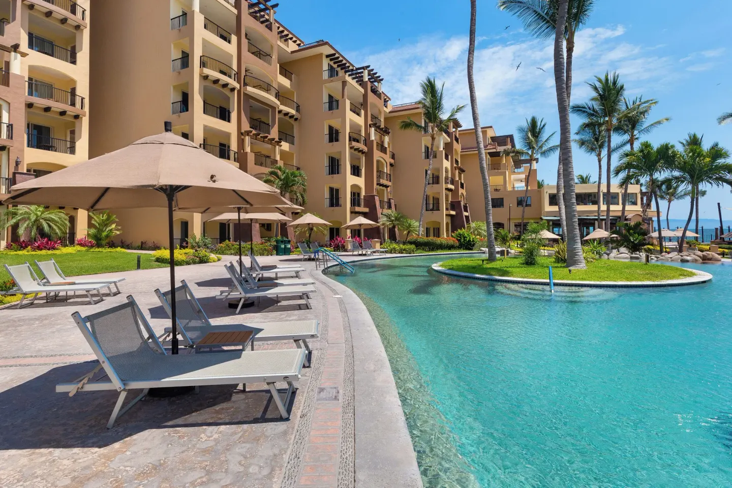 Poolside lounge chairs beside resort buildings at Villa Del Palmar Flamingos Beach Resort and Spa