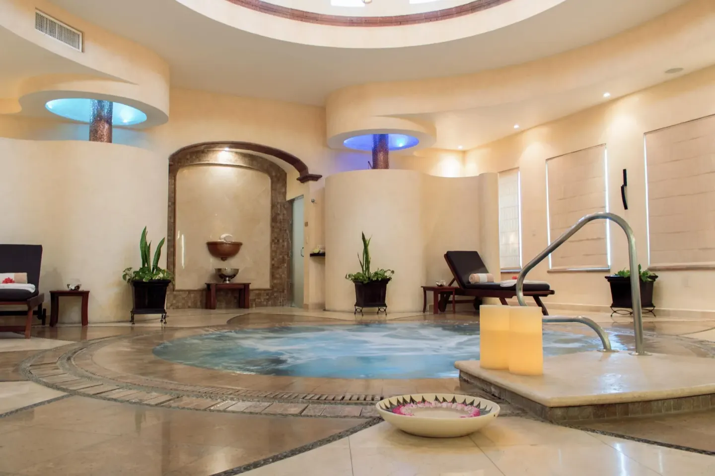 Spa pool with candles, loungers, and potted plants at Villa Del Palmar Flamingos Beach Resort and Spa.