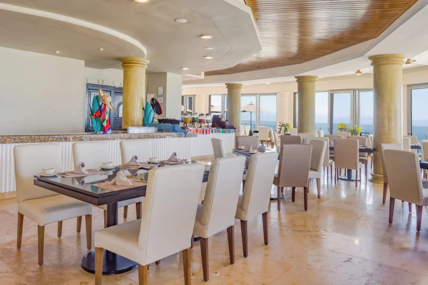 Bright indoor dining room with ocean-facing windows at Villa Del Palmar Flamingos Beach Resort and Spa.