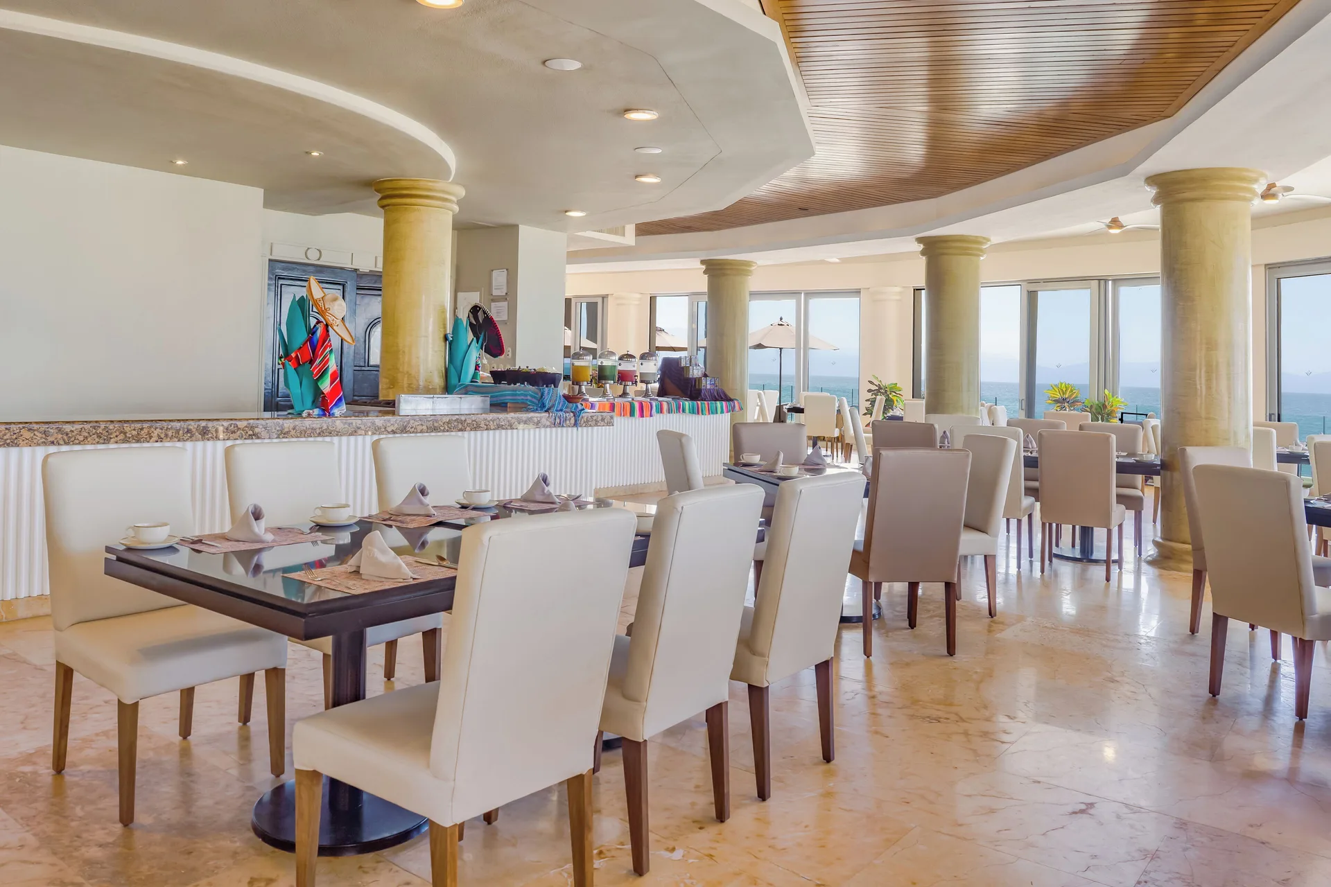 Bright indoor dining room with ocean-facing windows at Villa Del Palmar Flamingos Beach Resort and Spa.