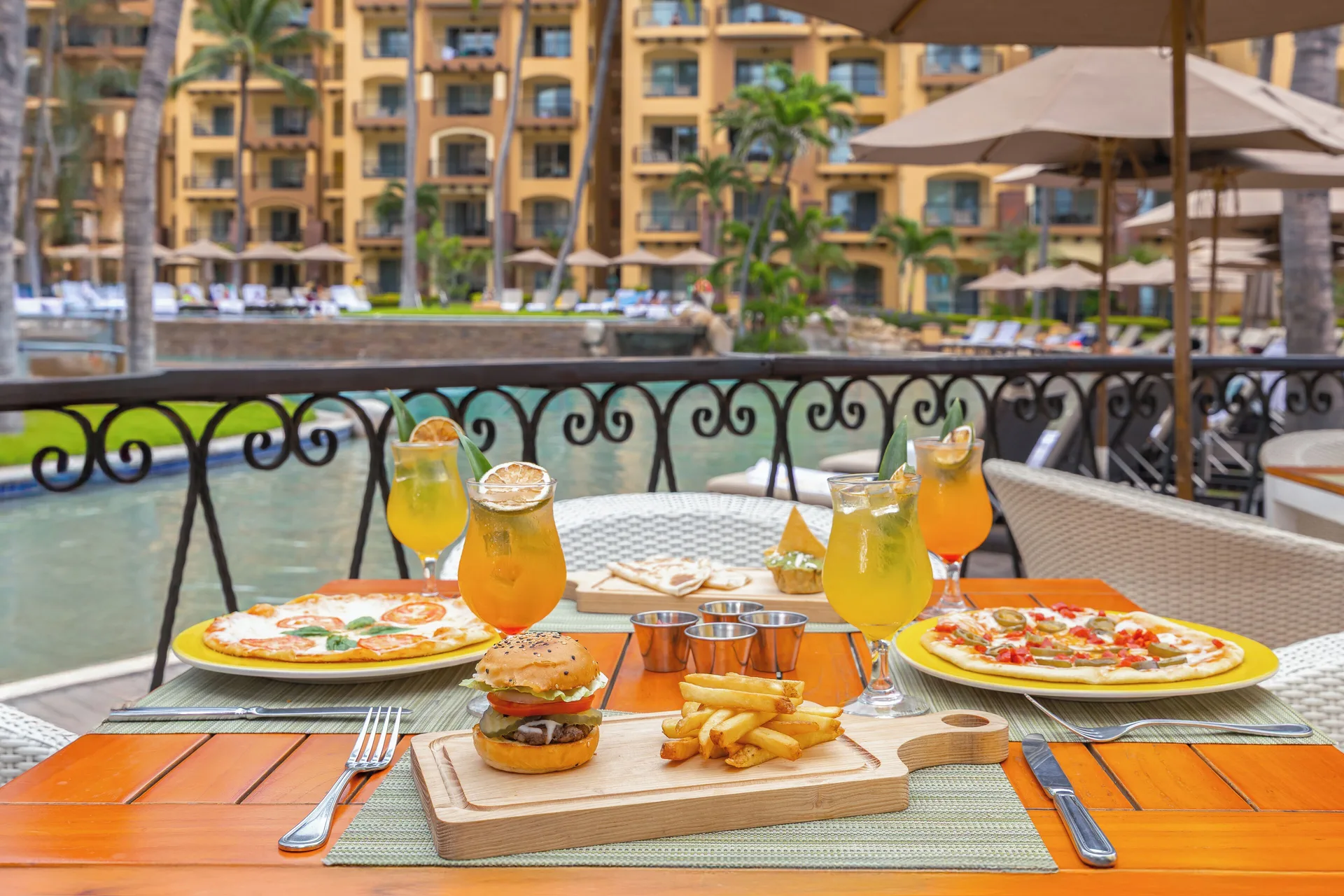 Poolside table with pizza, burger, fries and drinks at Villa Del Palmar Flamingos Beach Resort and Spa.