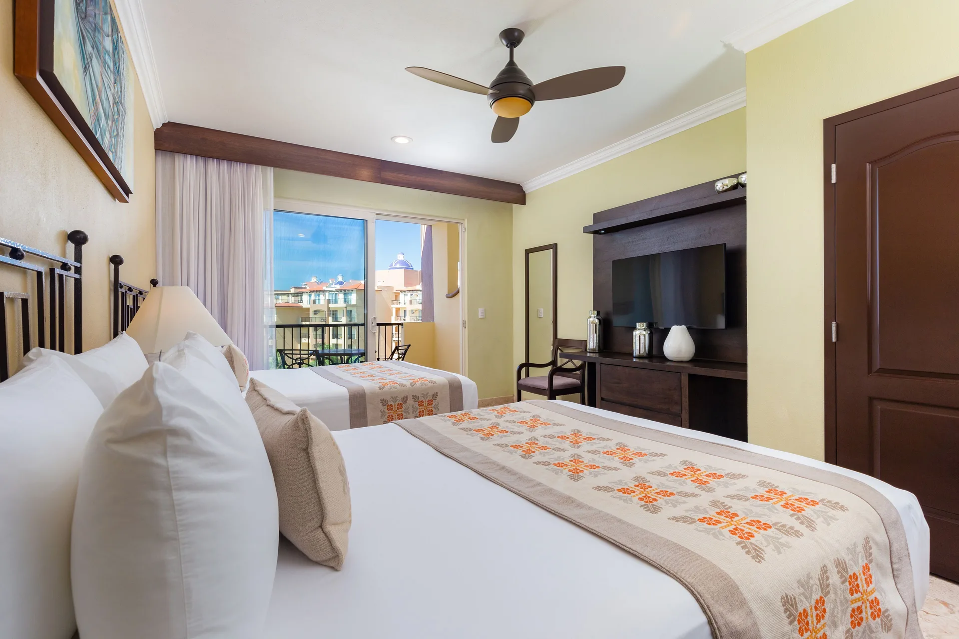 Junior Suite with two beds, TV, and balcony doors at Villa Del Palmar Flamingos Beach Resort and Spa.
