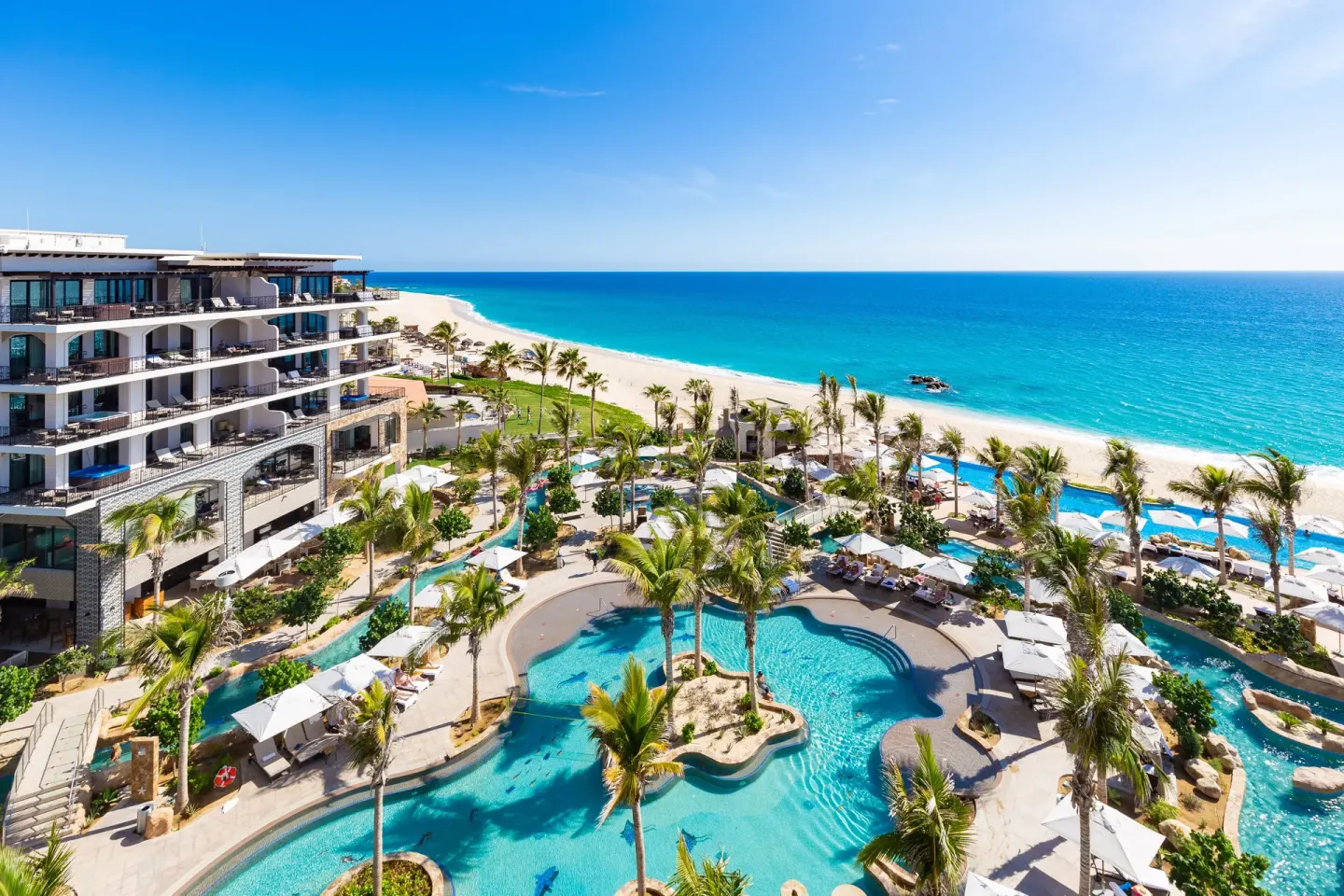 Aerial view of pools, palms, beach and ocean at Villa La Valencia Los Cabos Beach Resort & Spa.