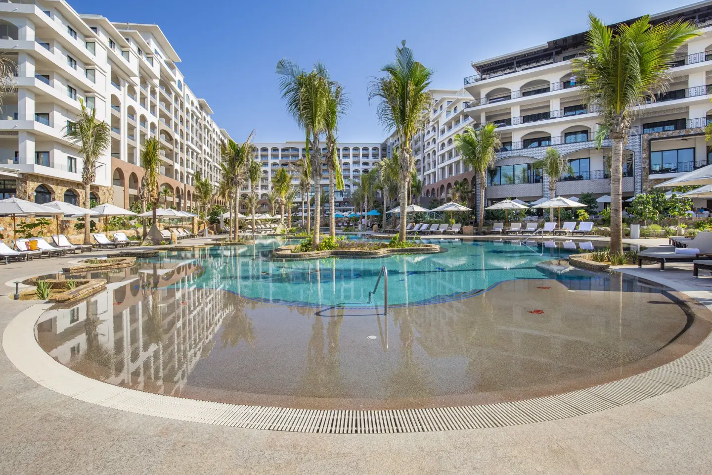 Large central pool courtyard with palms and loungers at Villa La Valencia Los Cabos Beach Resort & Spa.