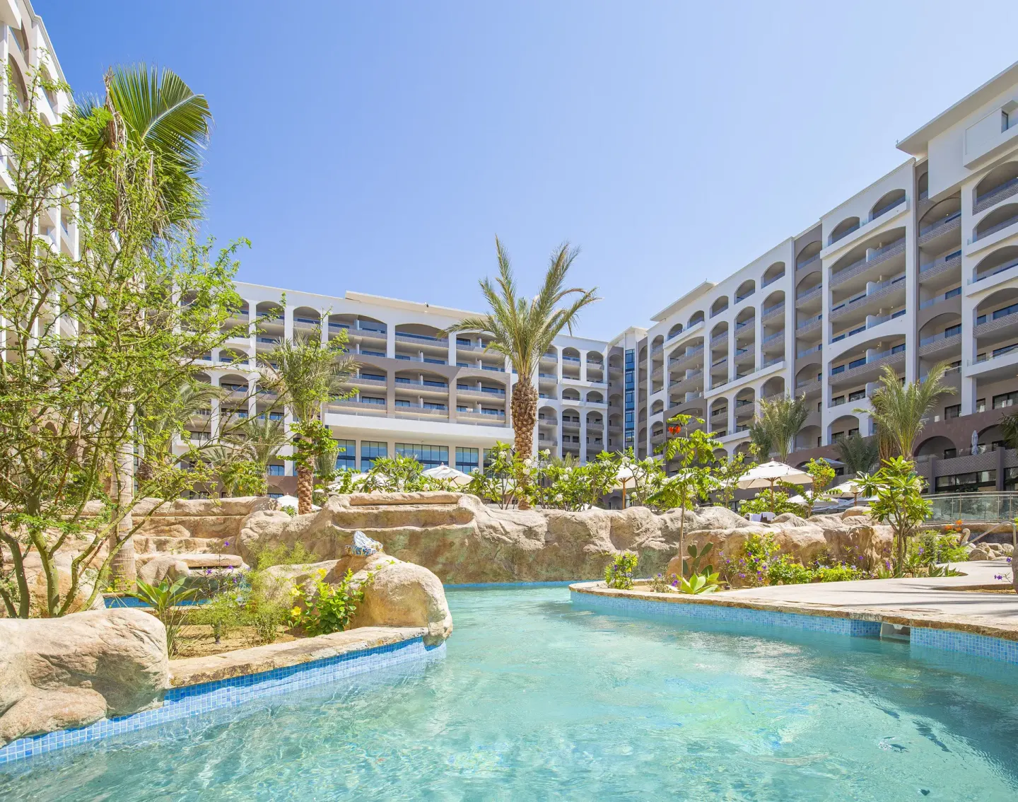 Courtyard pool with rock landscaping and arched buildings at Villa La Valencia Los Cabos Beach Resort & Spa.