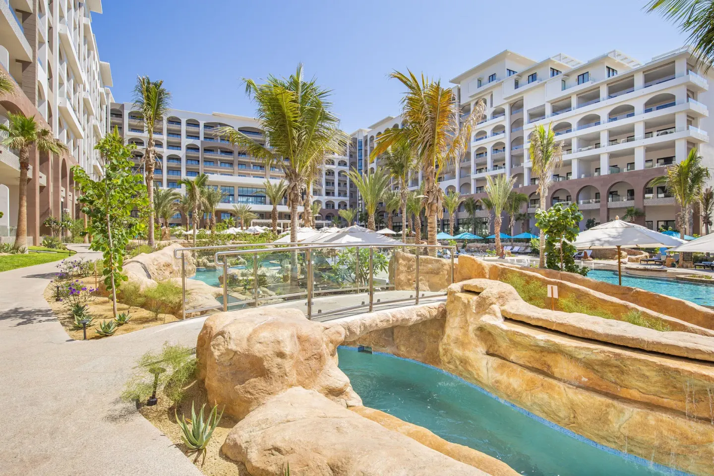 Glass footbridge over a narrow pool channel at Villa La Valencia Los Cabos Beach Resort & Spa.