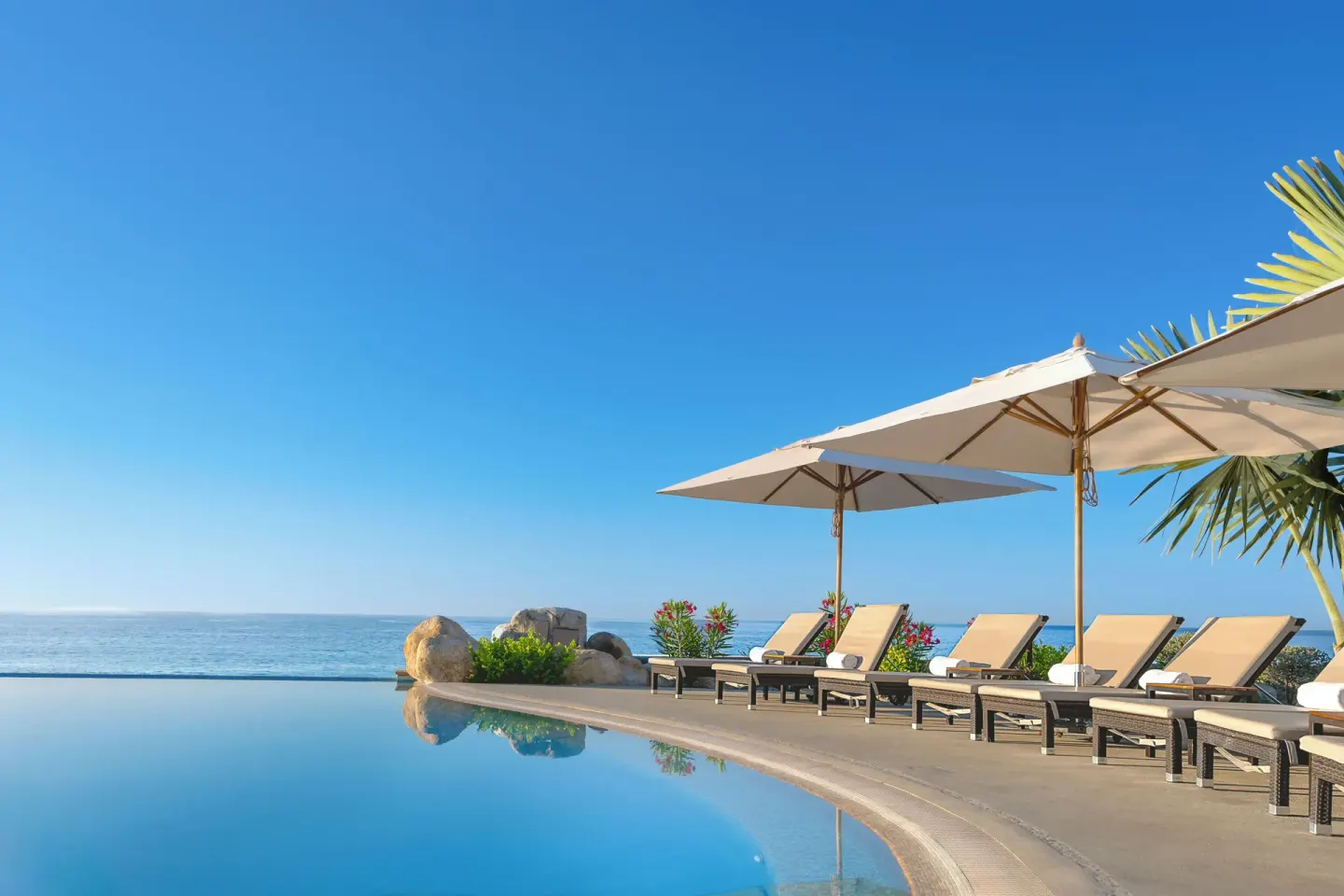 Infinity pool edge with ocean view and shaded loungers at Villa La Valencia Los Cabos Beach Resort & Spa.