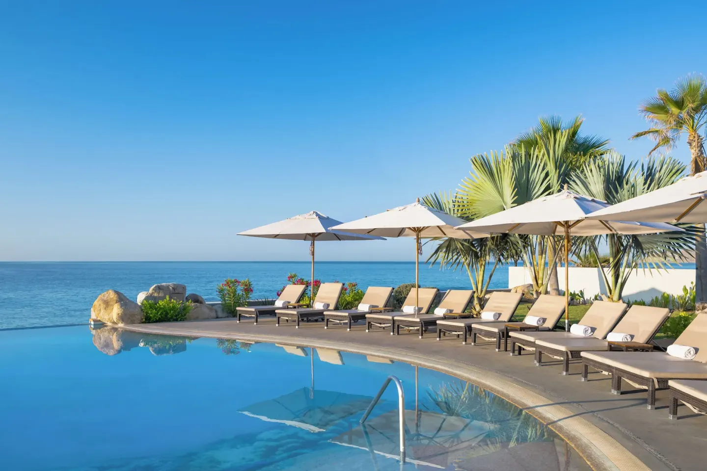 Infinity pool with loungers and ocean view at Villa La Valencia Los Cabos Beach Resort & Spa.
