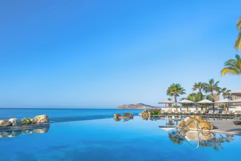 Infinity pool with ocean and distant coastline at Villa La Valencia Los Cabos Beach Resort & Spa.