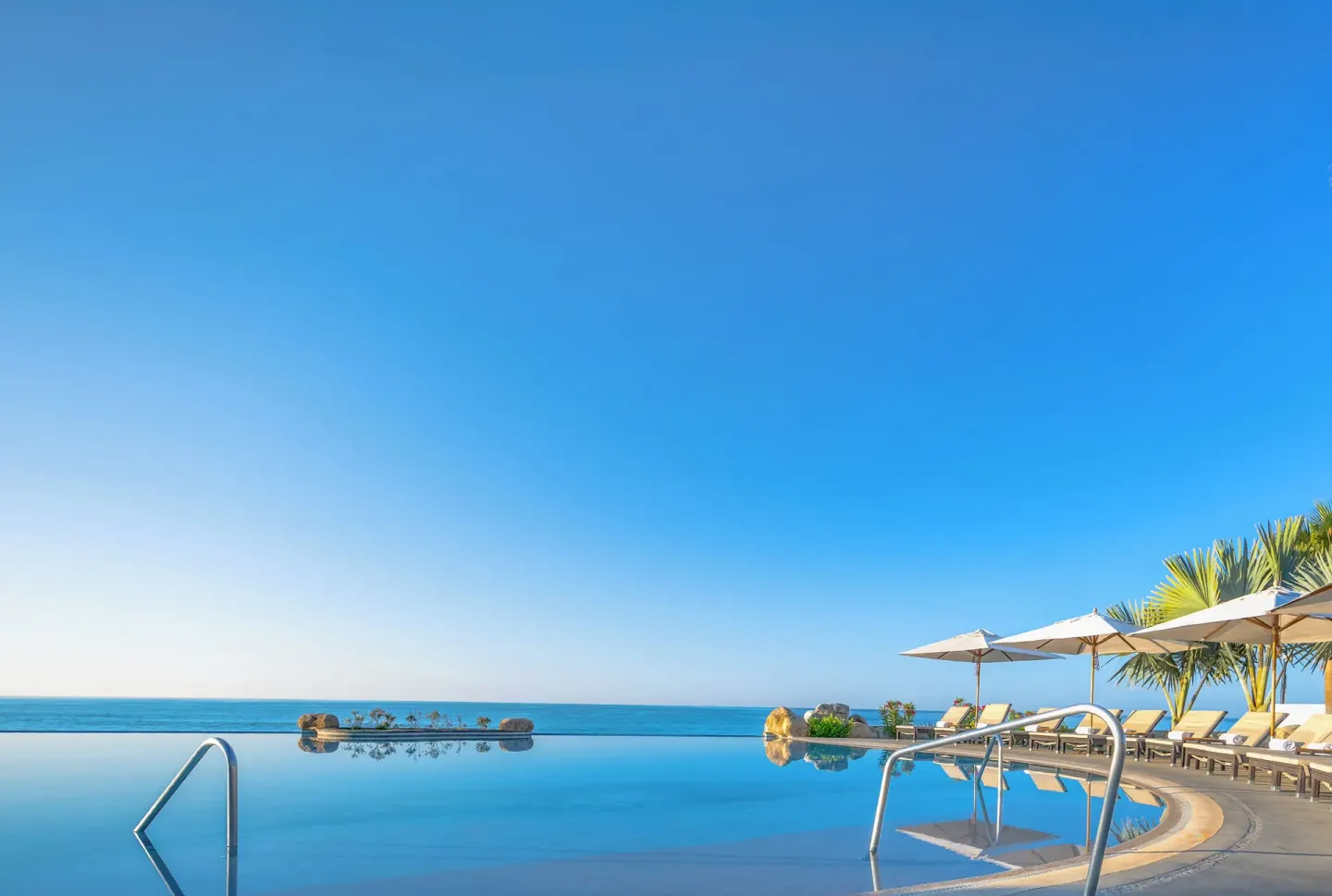 Infinity pool with ocean horizon and umbrella seating at Villa La Valencia Los Cabos Beach Resort & Spa.