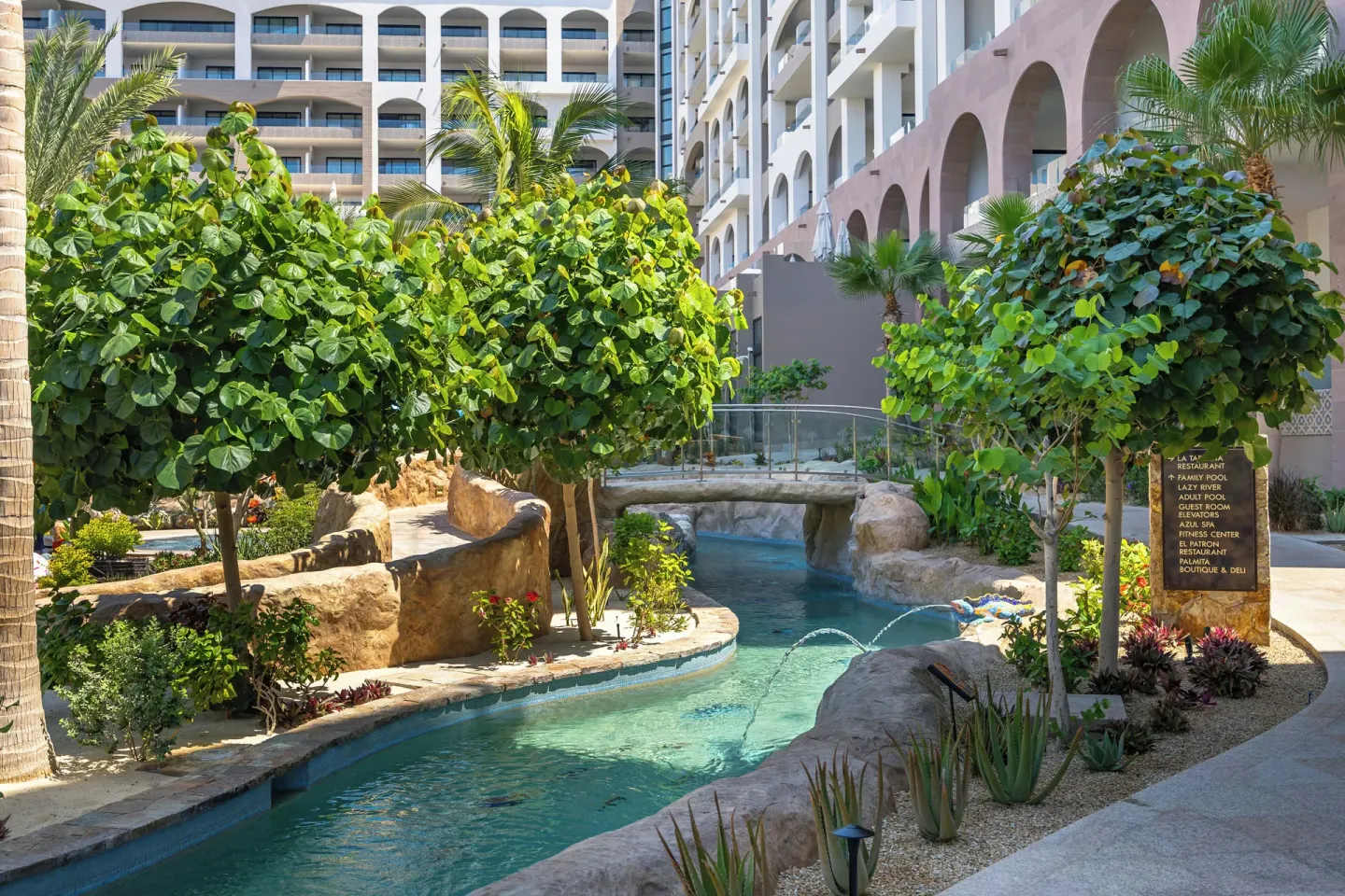 Landscaped lazy river with resort buildings at Villa La Valencia Los Cabos Beach Resort & Spa.