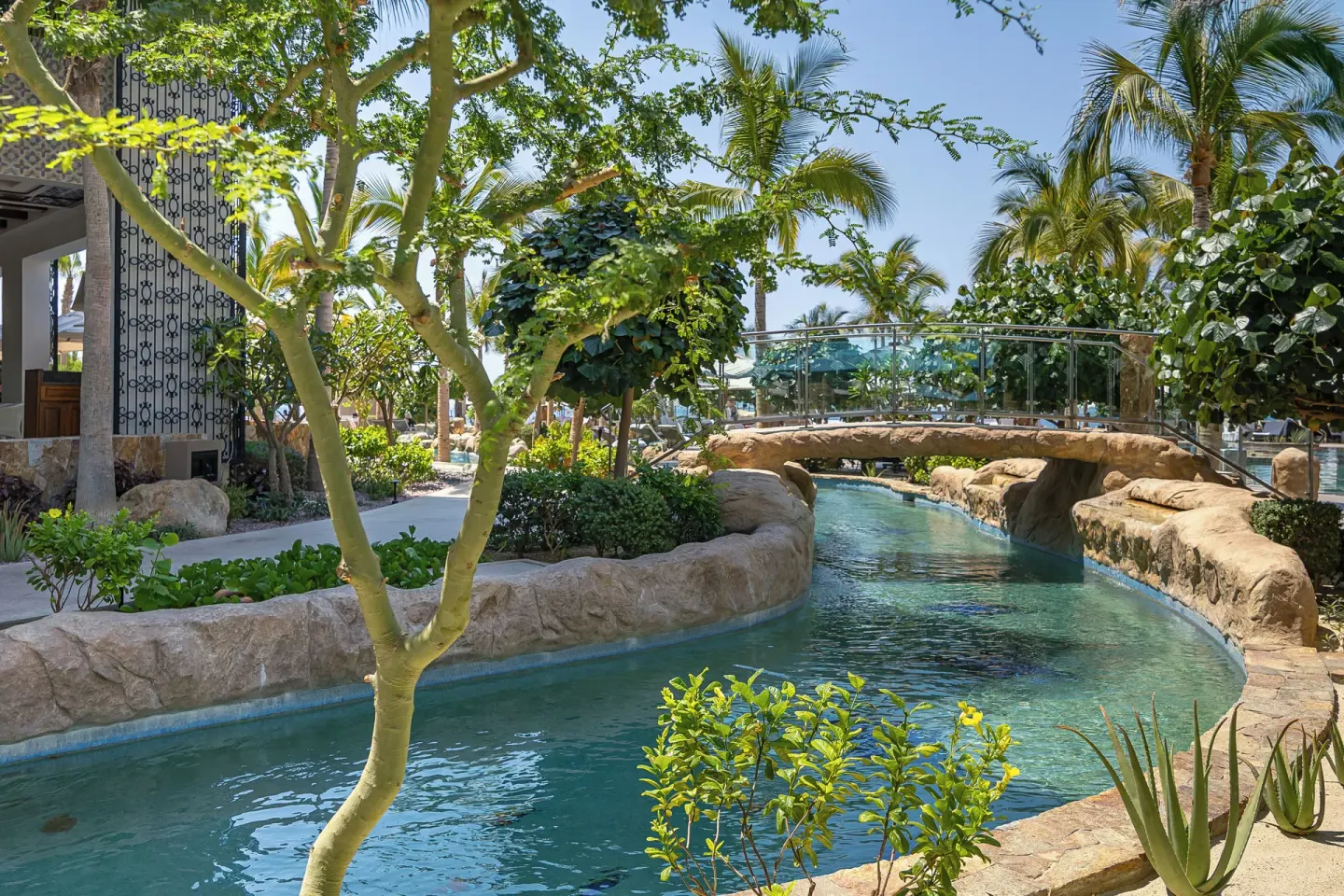 Lazy river beneath a glass footbridge at Villa La Valencia Los Cabos Beach Resort & Spa.