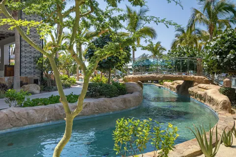 Lazy river beneath a glass footbridge at Villa La Valencia Los Cabos Beach Resort & Spa.