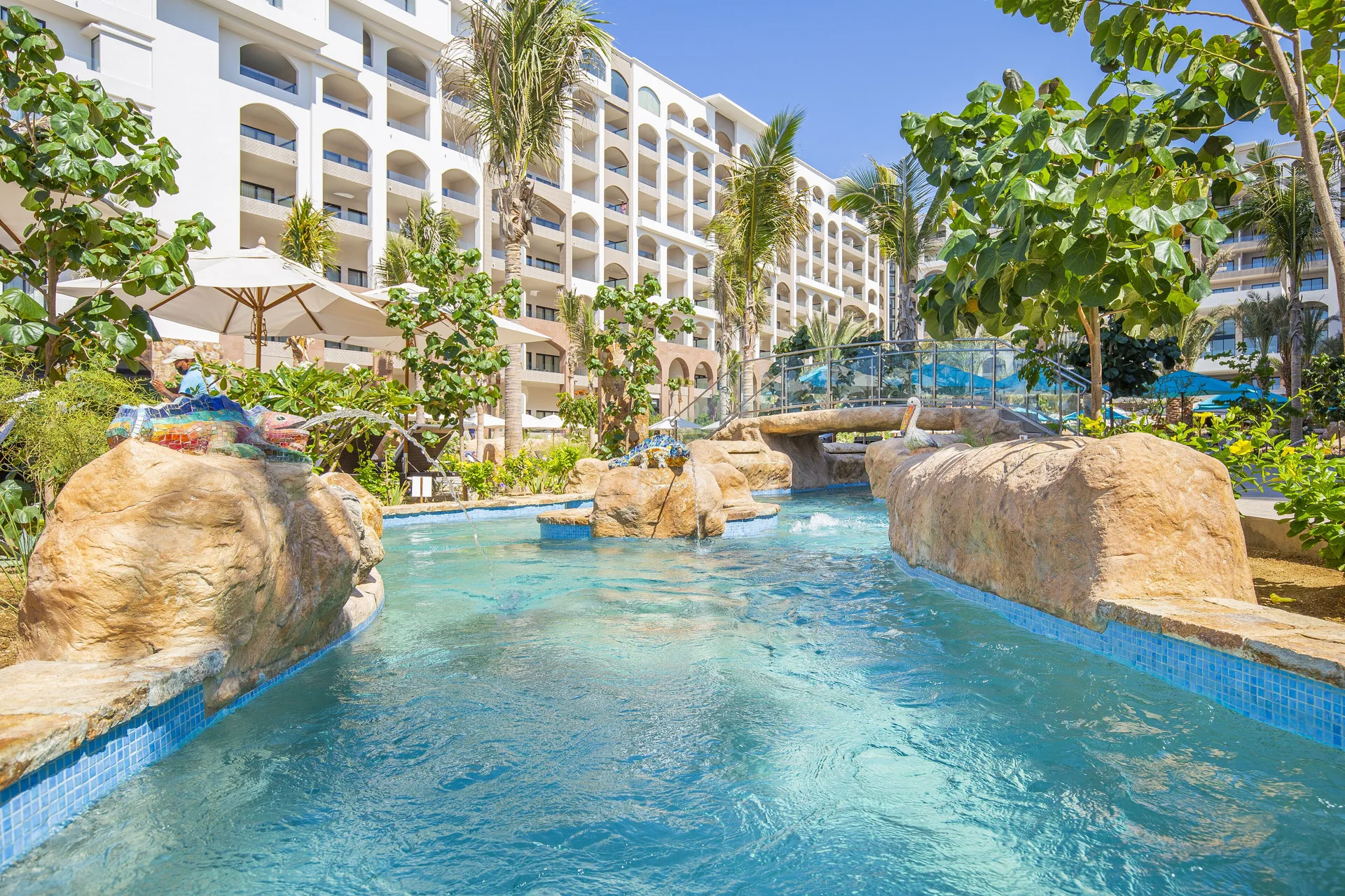 Lazy river pool with rocks and palms at Villa La Valencia Los Cabos Beach Resort & Spa.