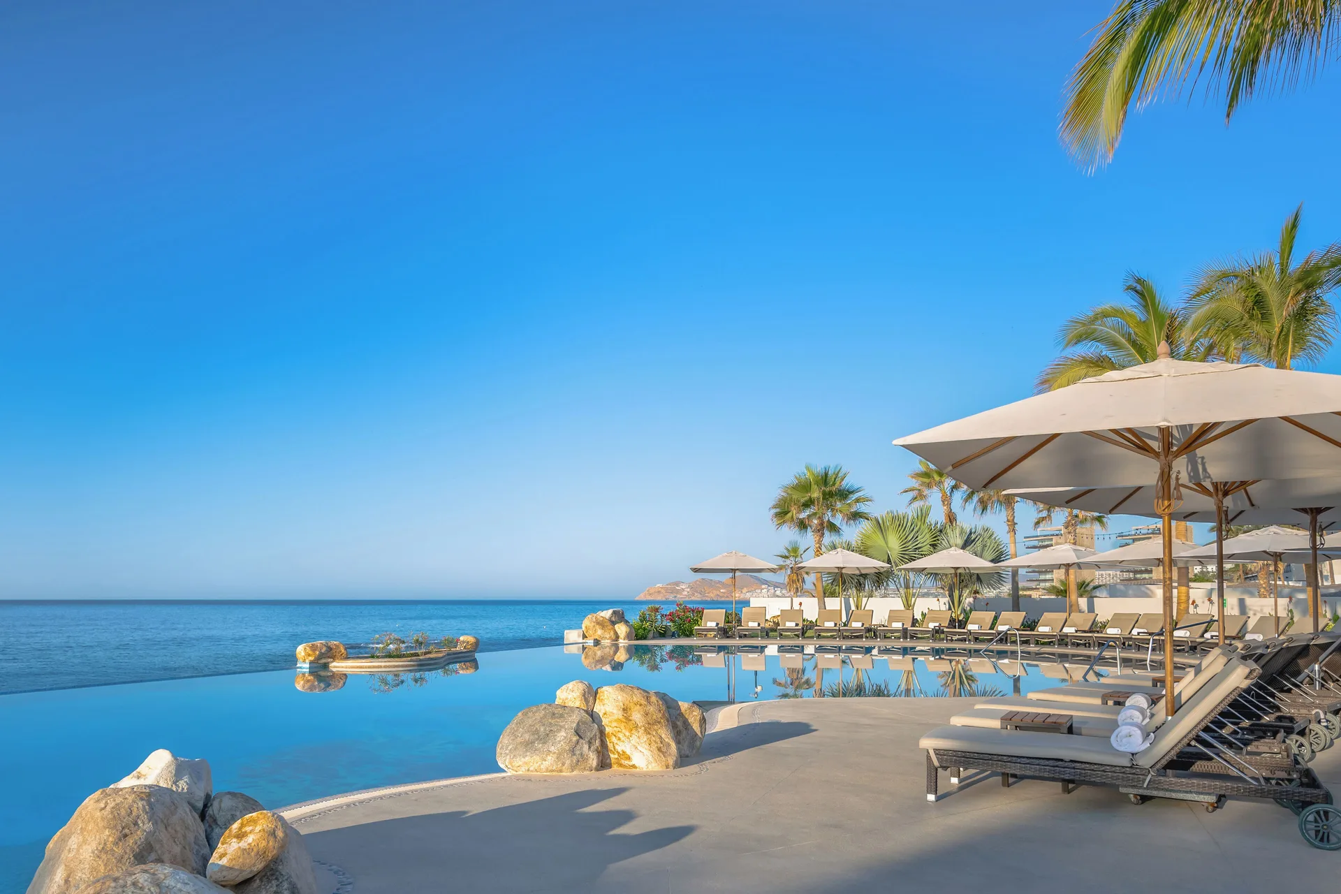Oceanfront infinity pool and shaded loungers at Villa La Valencia Los Cabos Beach Resort & Spa.