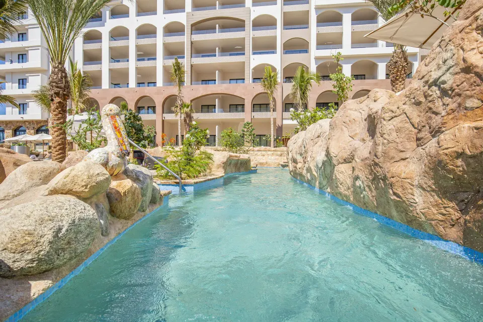 Rock-lined water channel and arched resort balconies at Villa La Valencia Los Cabos Beach Resort & Spa.