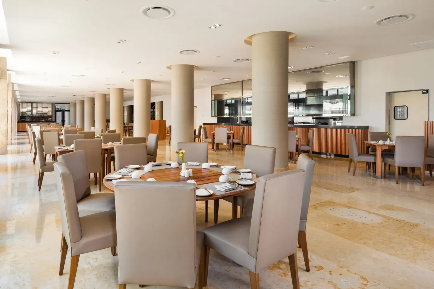 Indoor dining room with round tables at Villa La Valencia Los Cabos Beach Resort & Spa.