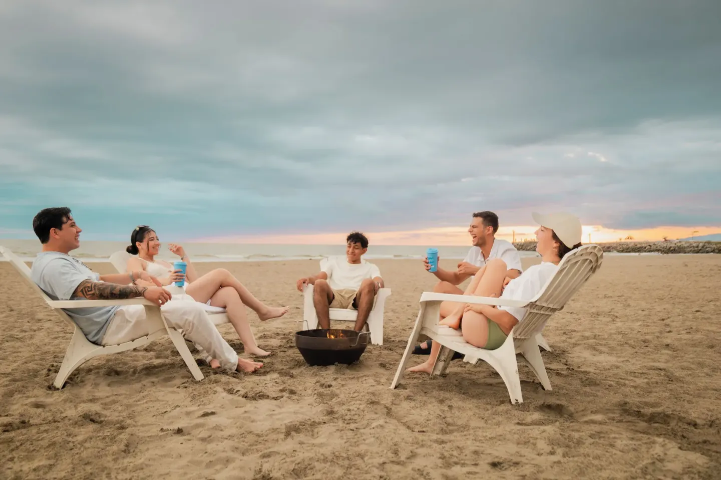 Guests sit around a small beach fire at sunset at Villa Varadero.