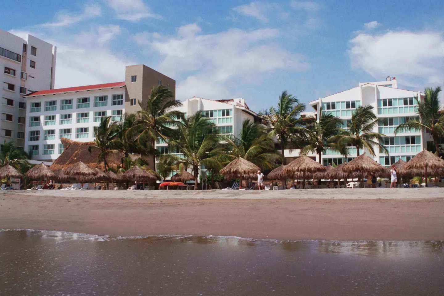 The beachfront side of Villa Varadero faces palapas and lounge chairs on the sand.