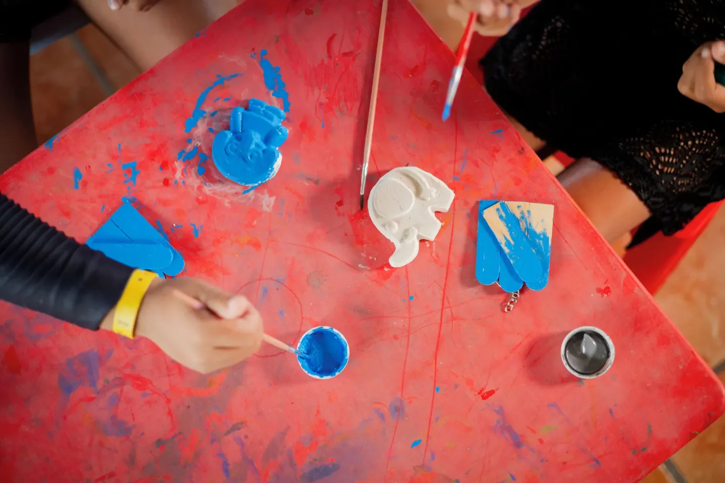 Children paint small crafts on a red activity table at Villa Varadero.
