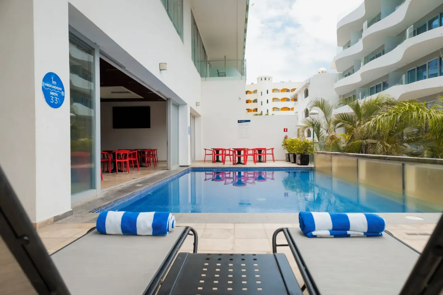 Two lounge chairs with striped towels facing a courtyard pool at Villa Varadero.