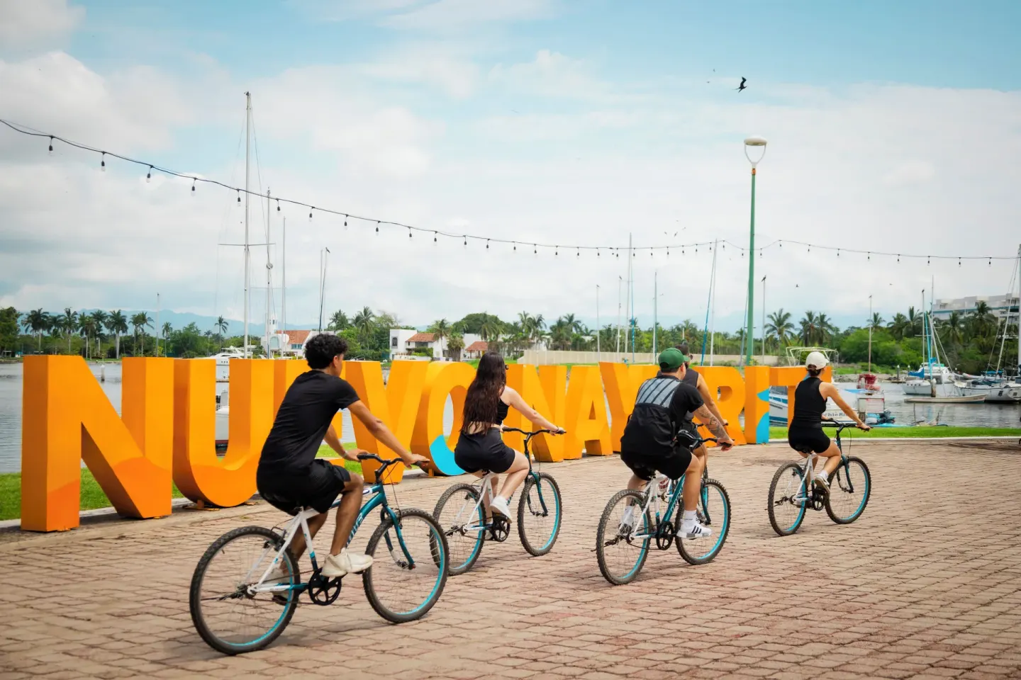 Cyclists pass a large Nuevo Nayarit sign near the marina by Villa Varadero.