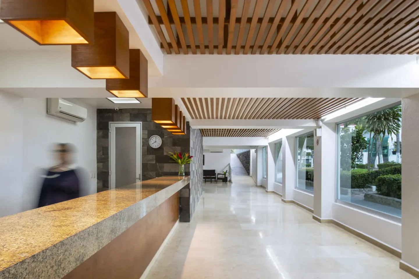 Lobby corridor with front desk, wood ceiling slats, and large windows at Villa Varadero.