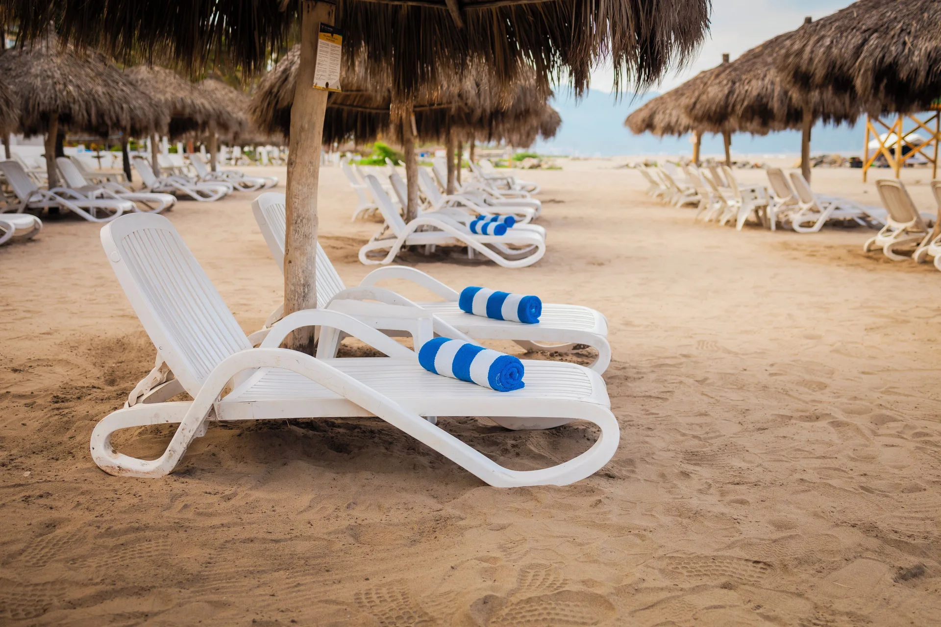 White loungers with blue towels under palapas at Villa Varadero.