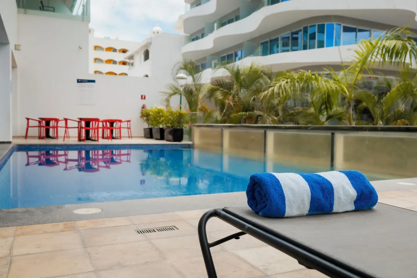 Poolside lounge chair with striped towel beside a small pool at Villa Varadero.
